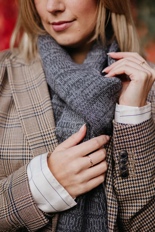 Detailaufnahme des Strickschals in Grau-Melange mit sichtbarer Strickstruktur.