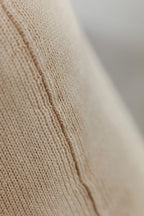 Detailaufnahme der Naht eines Strick-Dekokissens in der Farbe Cremebeige mit sichtbarer Struktur des Strickmaterials.