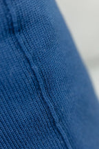 Detailaufnahme der Naht eines Strick-Dekokissens in der Farbe Indigoblau mit sichtbarer Struktur des Strickmaterials.