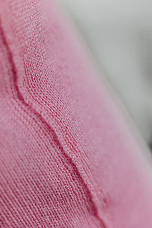 Detailaufnahme der Naht eines Strick-Dekokissens in der Farbe Rosa mit sichtbarer Struktur des Strickmaterials.