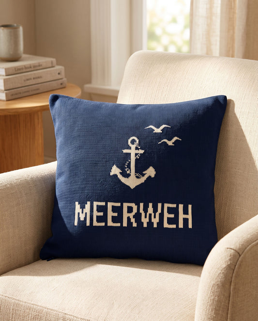 Dunkelblaues Kissen mit Anker, Möwen und der Aufschrift „MEERWEH“ auf Sessel.
