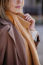 Detailaufnahme des Strickschals in Curry-Melange mit feiner Strick-Struktur.