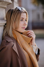 Strickschal in Curry-Melange getragen von Frau im Porträt.