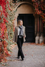 Frau trägt Strickschal in Grau-Melange vor herbstlicher Kulisse im Lifestyle-Bild.