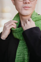 Detailaufnahme des Strickschals in Grün-Melange mit sichtbarer Strickstruktur am Hals getragen.