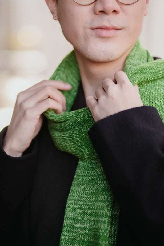 Detailaufnahme des Strickschals in Grün-Melange mit sichtbarer Strickstruktur am Hals getragen.
