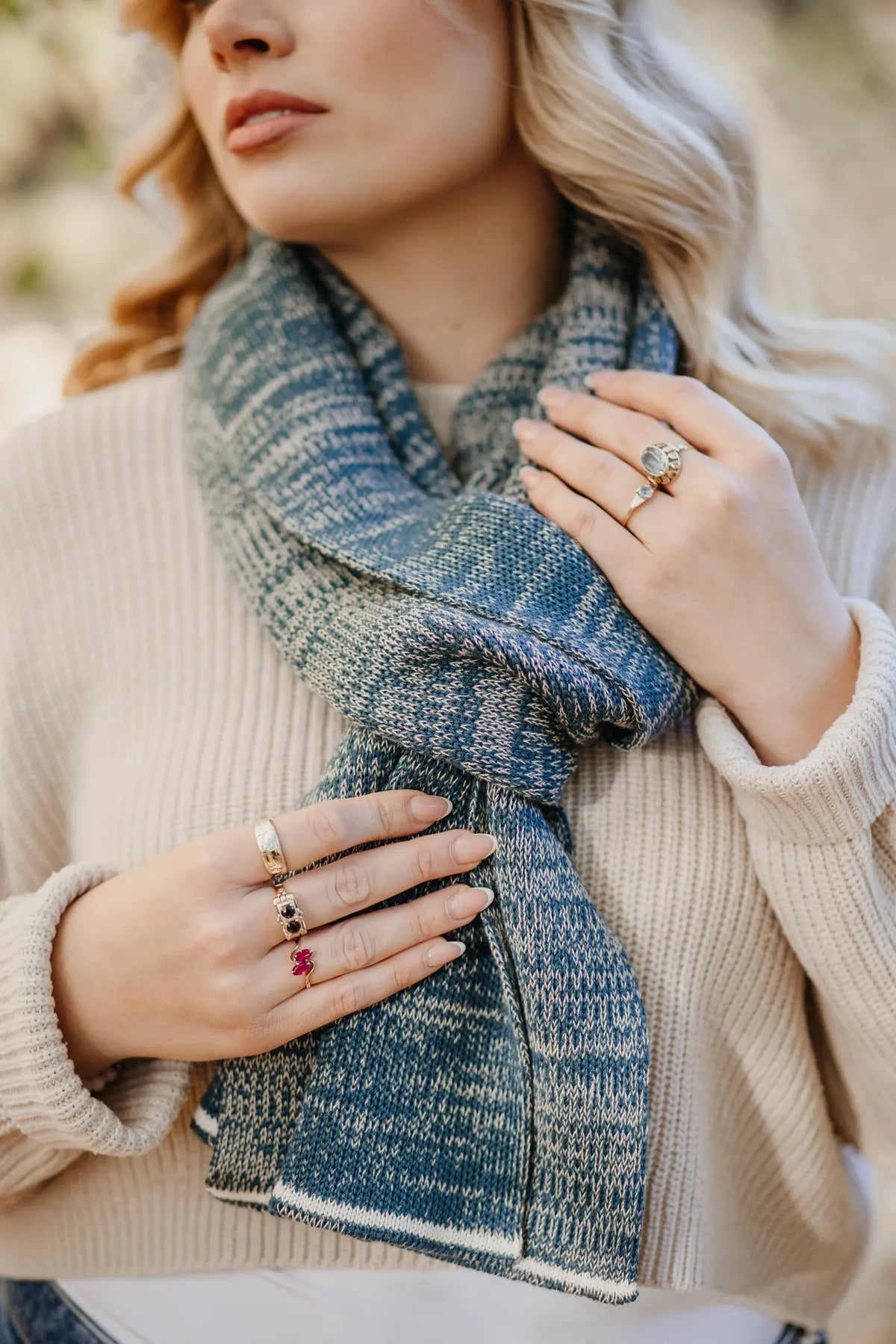 Strickschal in Petrol-Melange mit feiner Strickstruktur, um den Hals getragen.