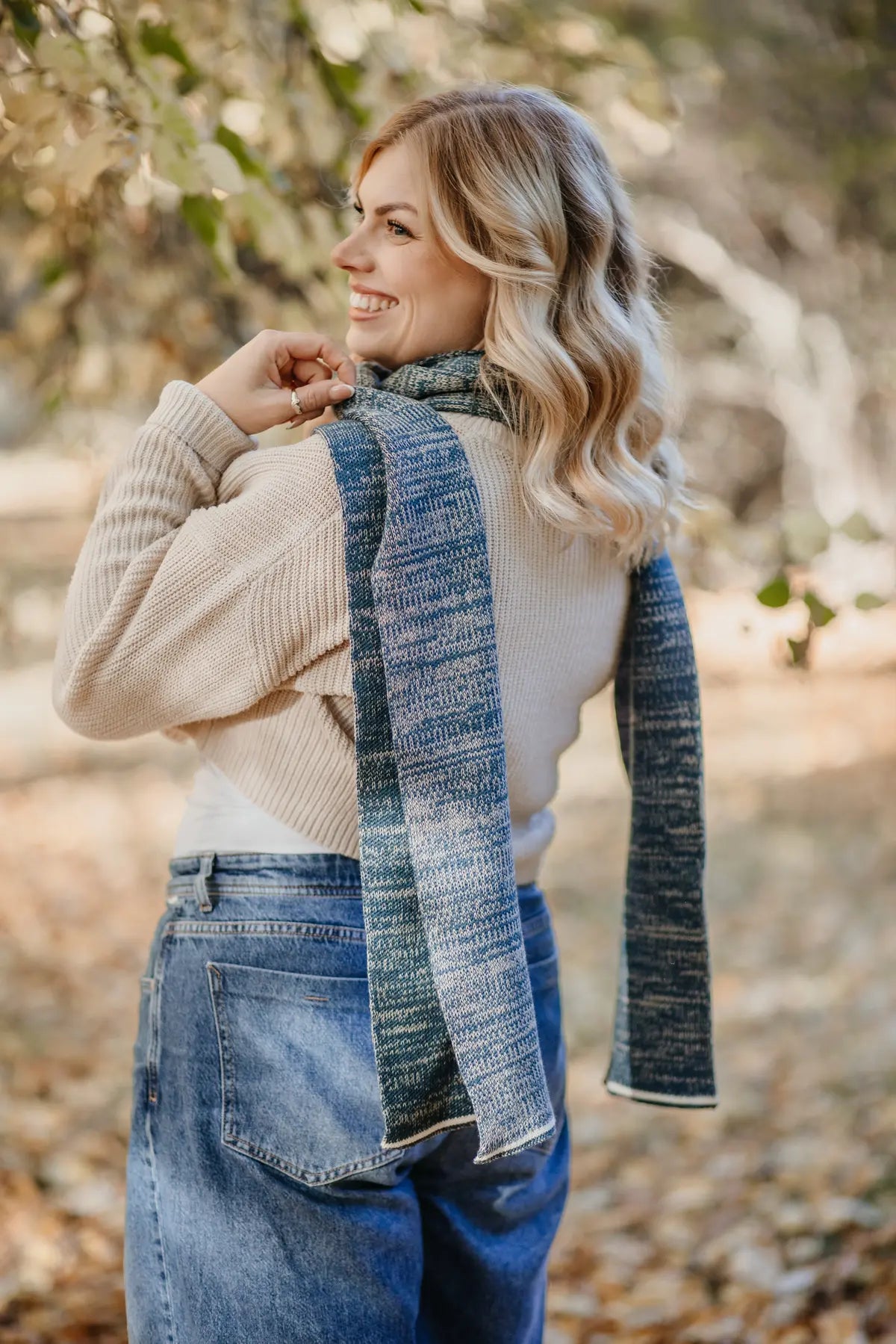 Frau trägt Petrol melierten Strickschal kombiniert mit Strickpullover im Outdoor-Bereich.
