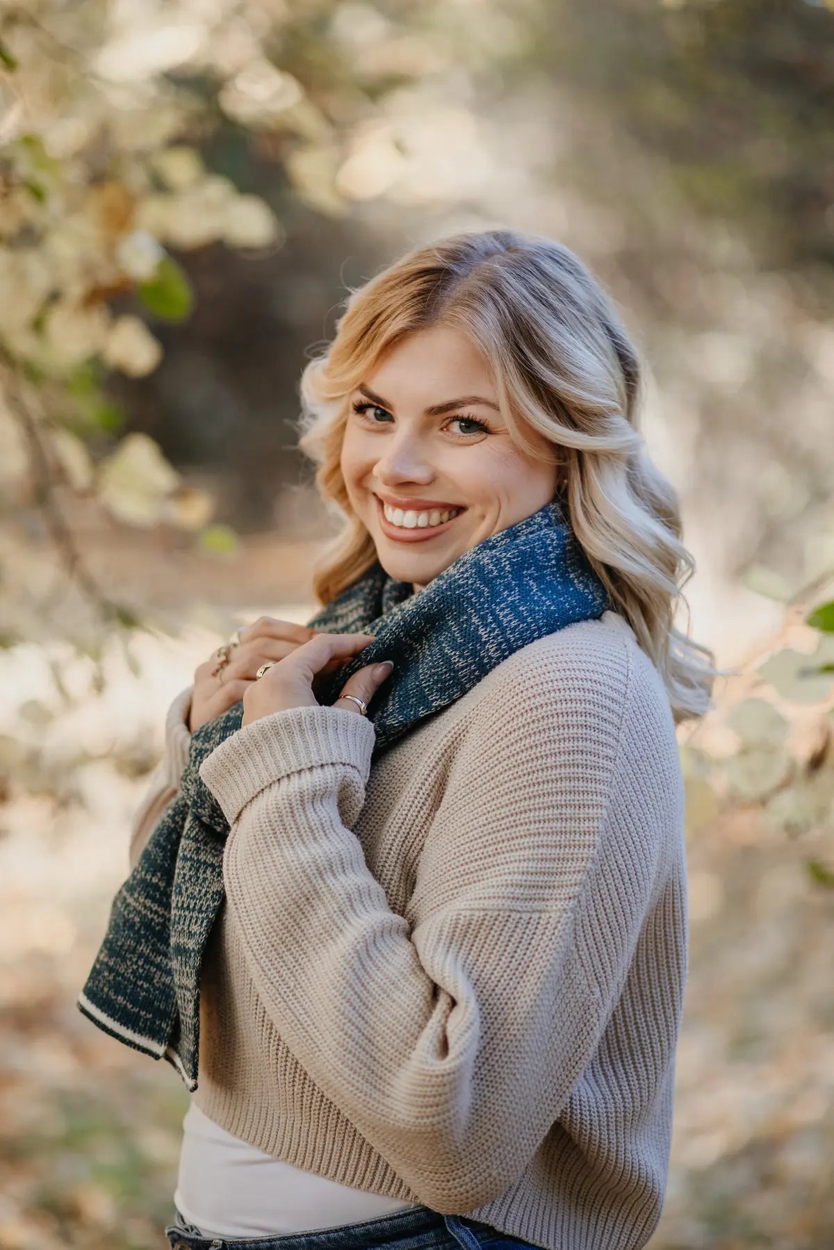 Strickschal in Petrol-Melange getragen von Frau im herbstlichen Außenbereich.